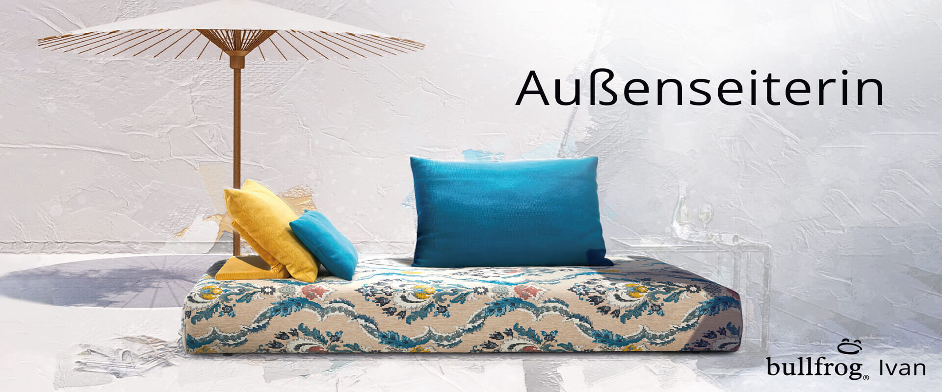 Stilvolles Designmöbel von Ottensmeyer, ideal für entspannende Stunden im Freien, mit bunten Kissen und Sonnenschirm.